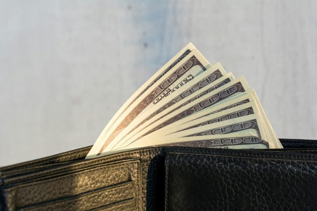 A close-up image of a wallet with 100 dollar bills sticking out of it.