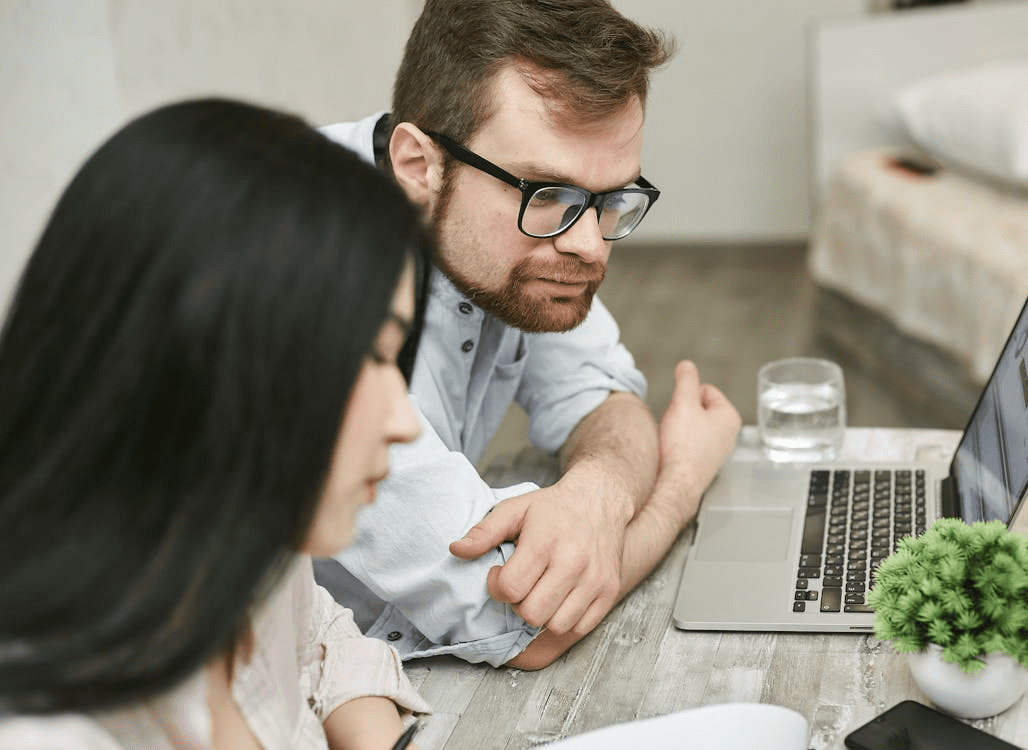 An image of a man and a woman sitting at a table in front of a laptop