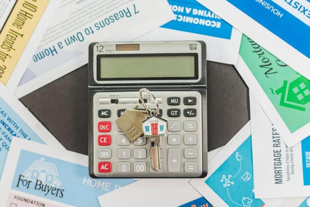 An image of a calculator with house keys on top surrounded by scattered papers related to investing