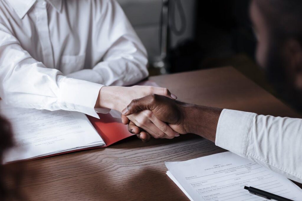 two individuals shaking hands amidst a loan agreement
