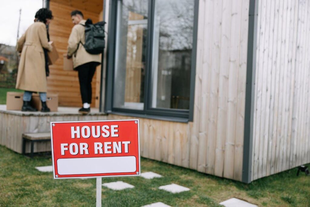 An image of a house for rent sign and two people entering a house in the background