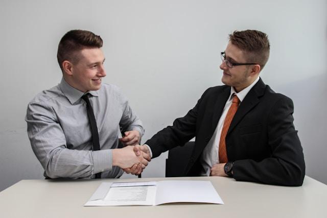 This photo shows two people shaking hands over open documents