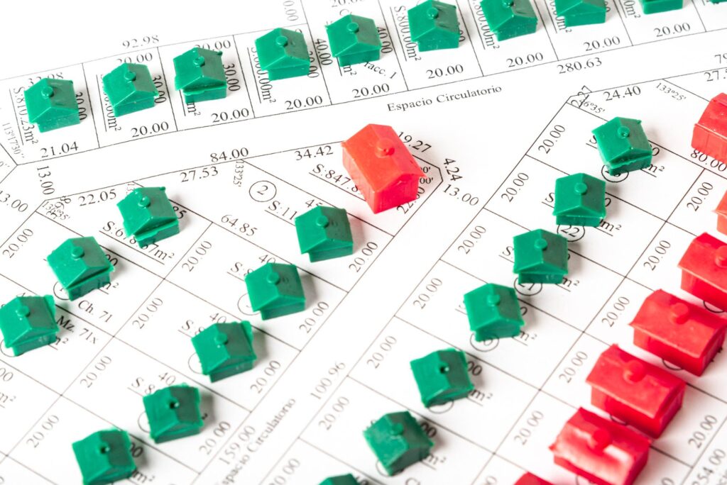 Red and green toy houses arranged on a financial rate sheet or chart