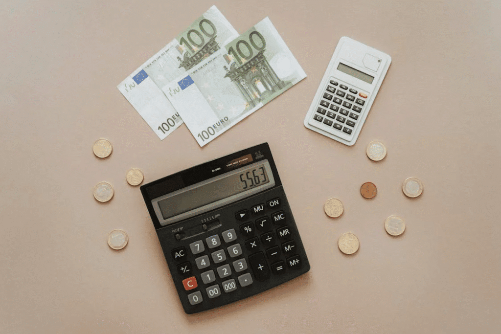 Black and silver calculator beside stacks of silver coins and notes
