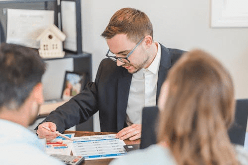 Real estate agent sitting at a table discussing paperwork with a client.