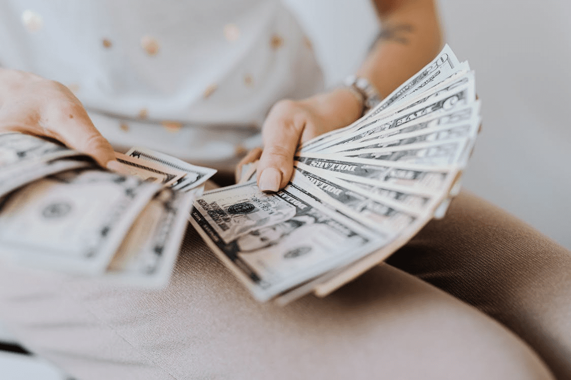 Person counting dollar bills representing cash received from a refinance loan