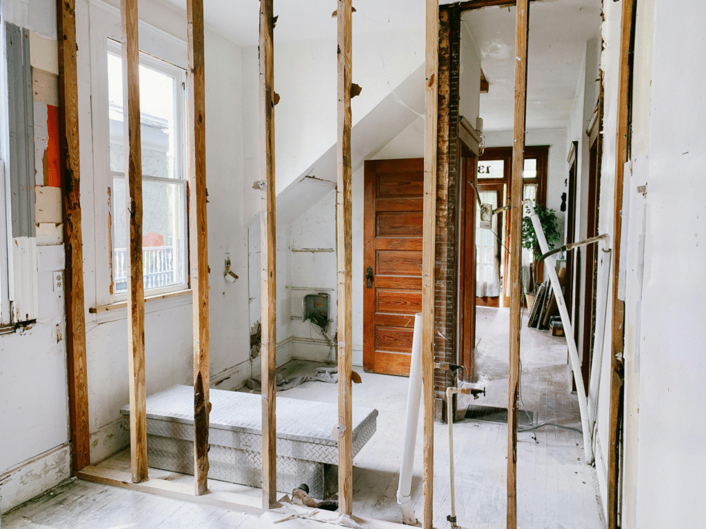 a house with white walls and wooden doors, under renovation