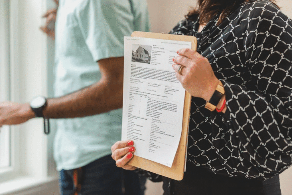 a woman holding a clipboard with a rental property paper on it, standing next to a man by the window