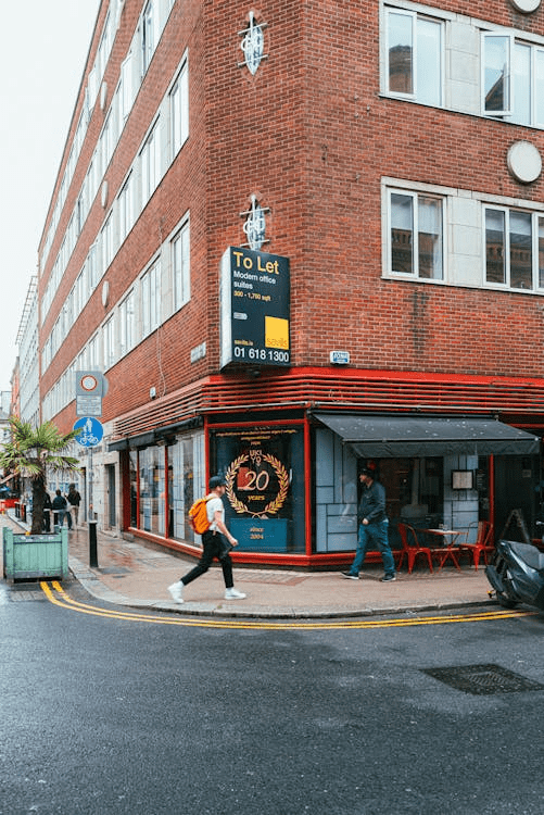 An image of a street focused on a mixed-use corner building with people walking.