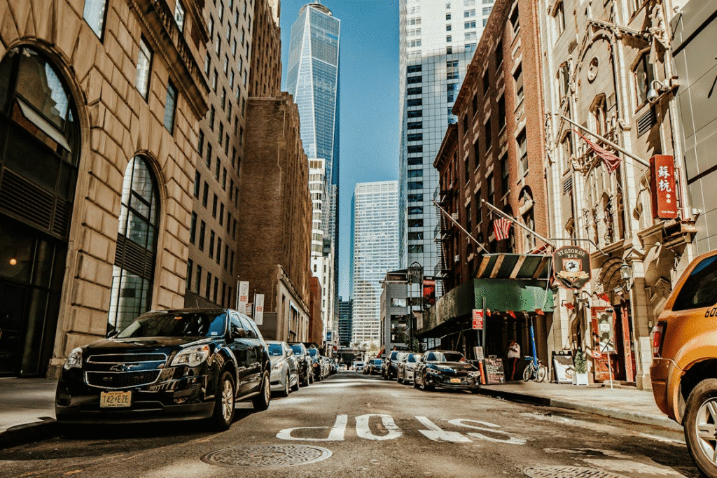 An image showing a street with multiple mixed-use buildings, cars, and skyscrapers in the background.