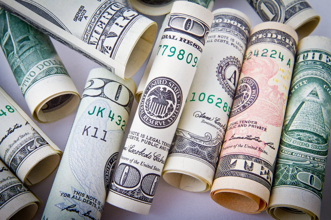 A close-up image of multiple rolled-up dollar bills.