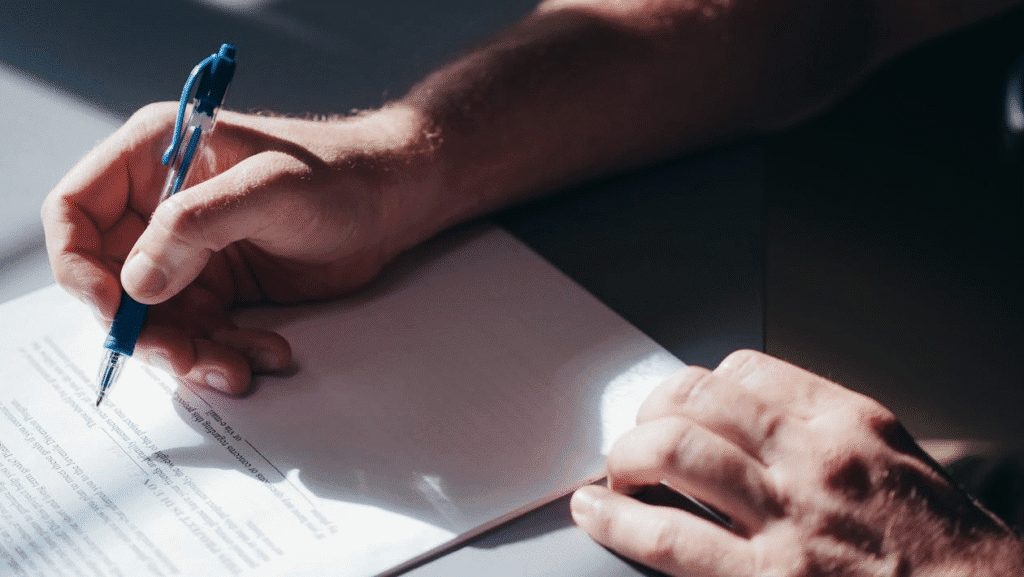 close-up of a person's hands about the sign a document on a table