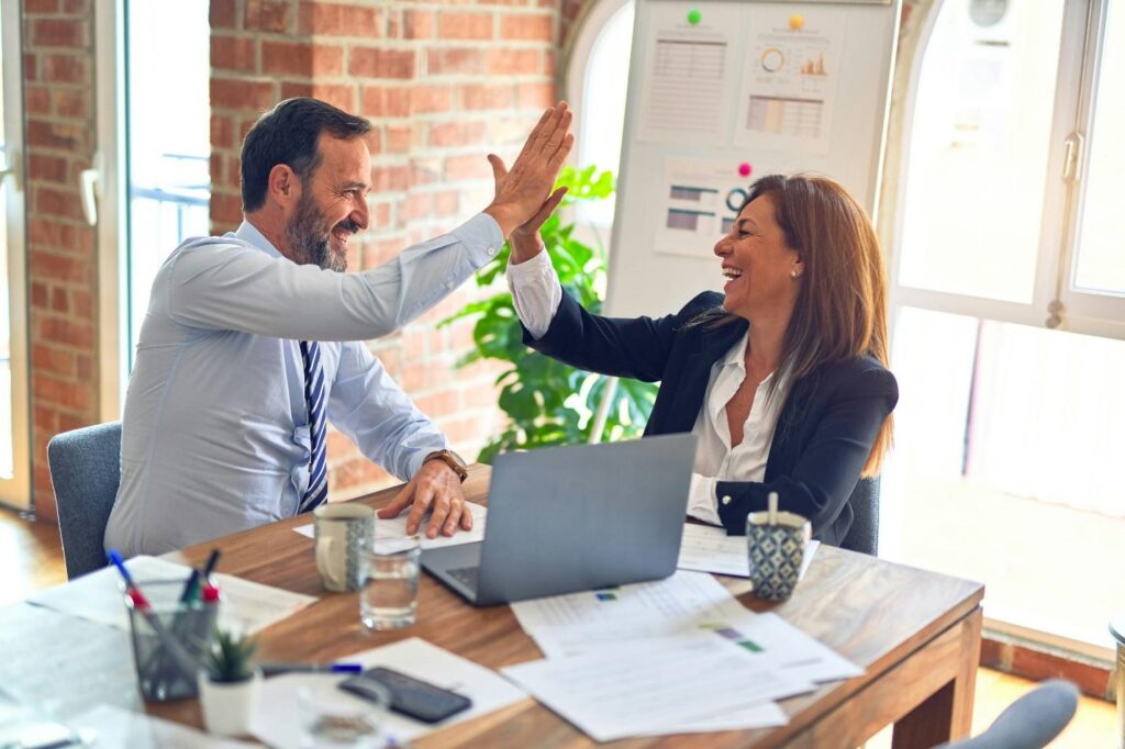 A man and a woman during a high-five in a corporate meeting setting