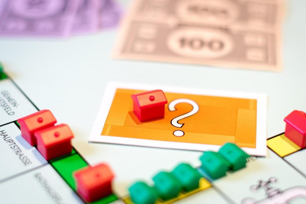 A monopoly board with multiple miniature houses with one resting on a card with a question mark