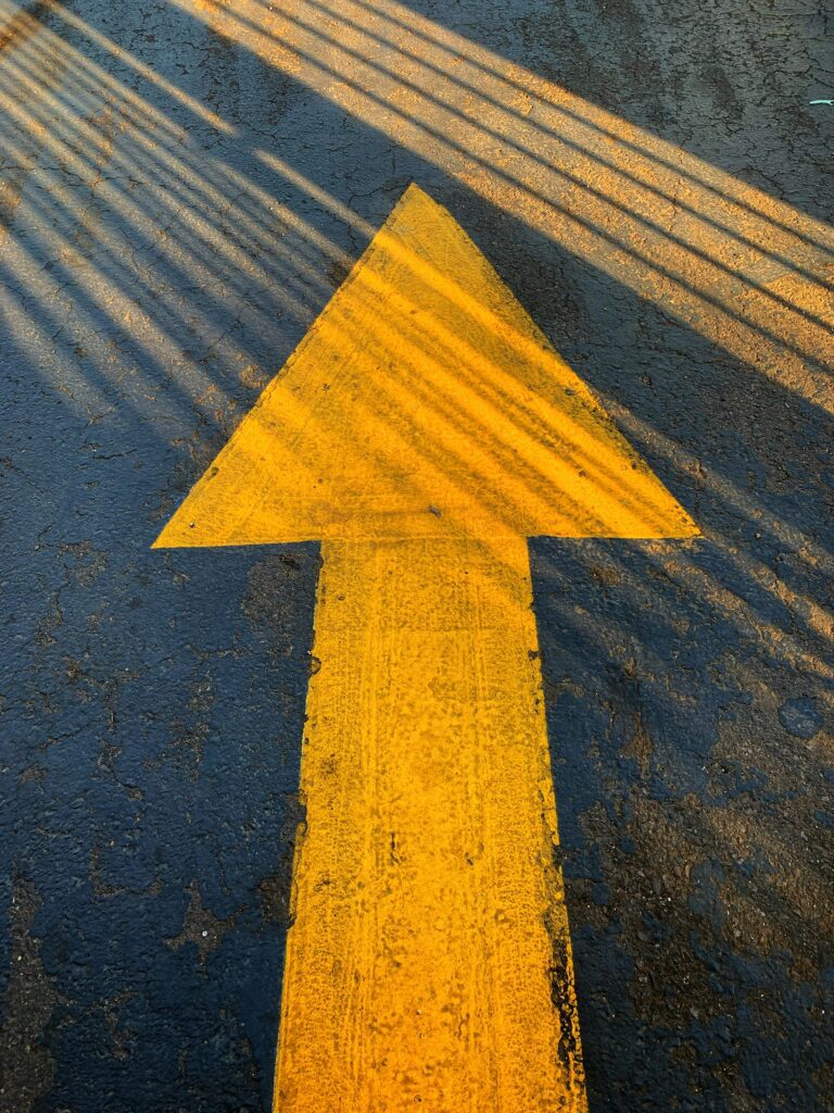 A yellow directional arrow painted on a gray concrete road
