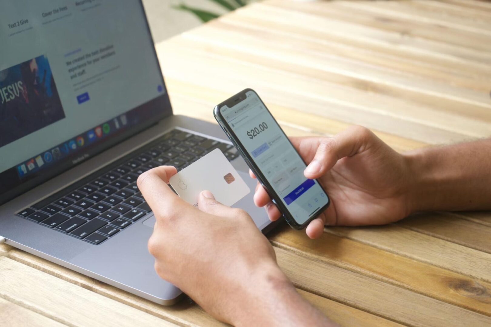 Image of a laptop and hands holding a phone and a card in front of it