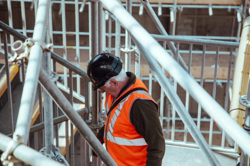 Construction worker standing beneath metal scaffolding at a construction site