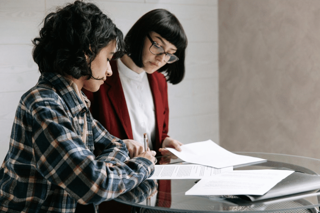 Two professional women reviewing and signing investment property loan documents