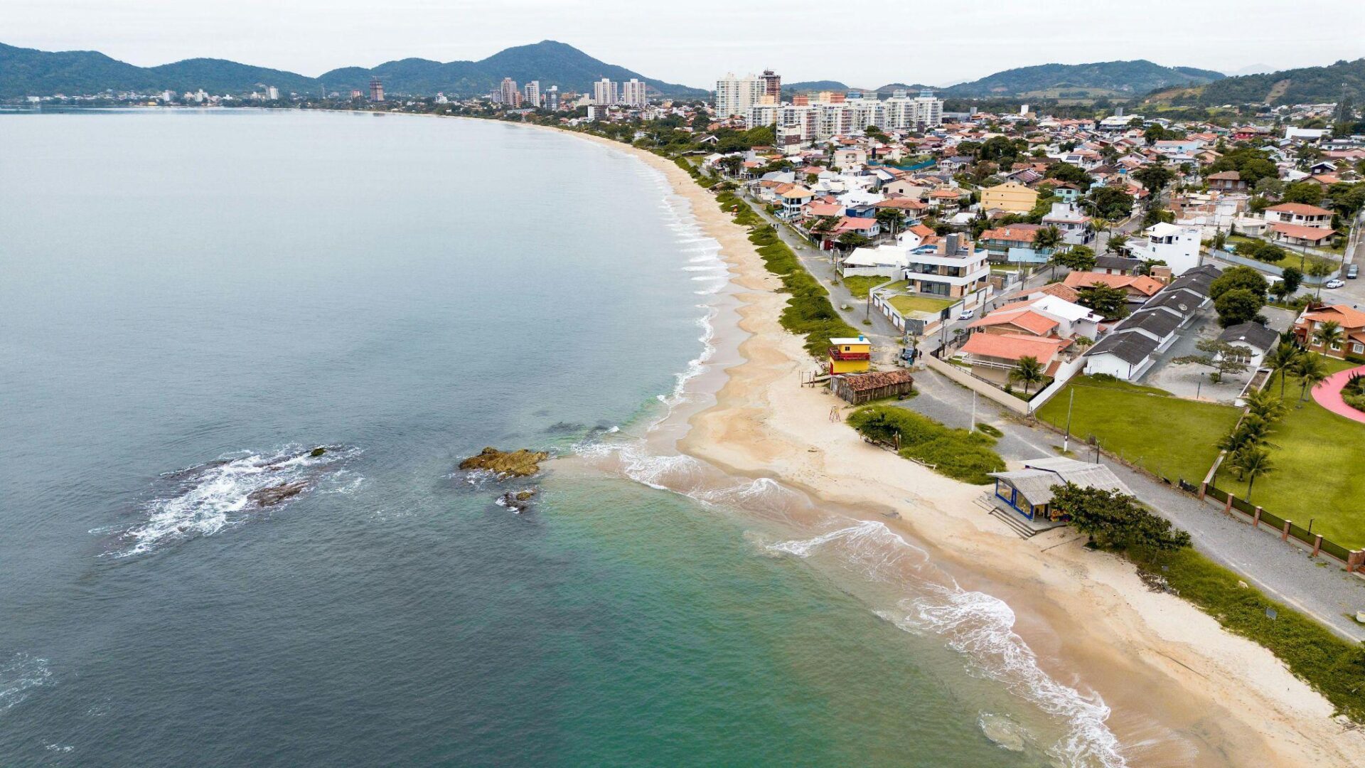 A photo showing a coastal area with houses lining the beach.