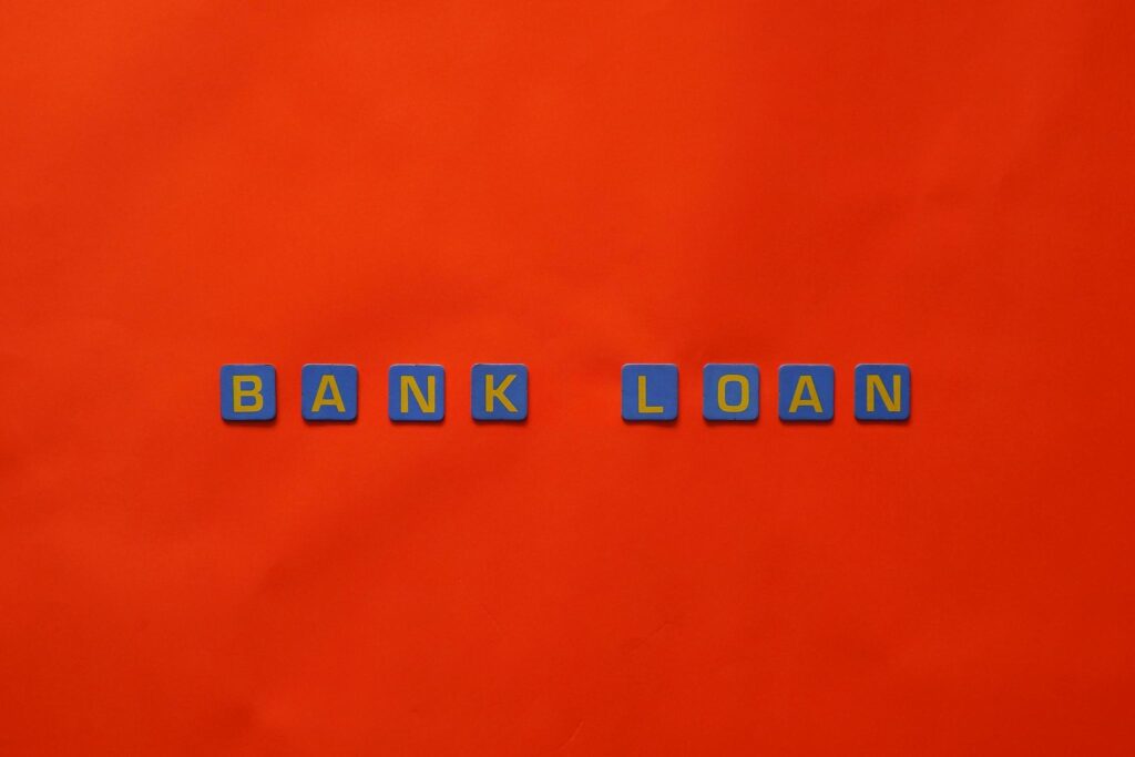 a red surface with Scrabble tiles spelling “bank loan.”