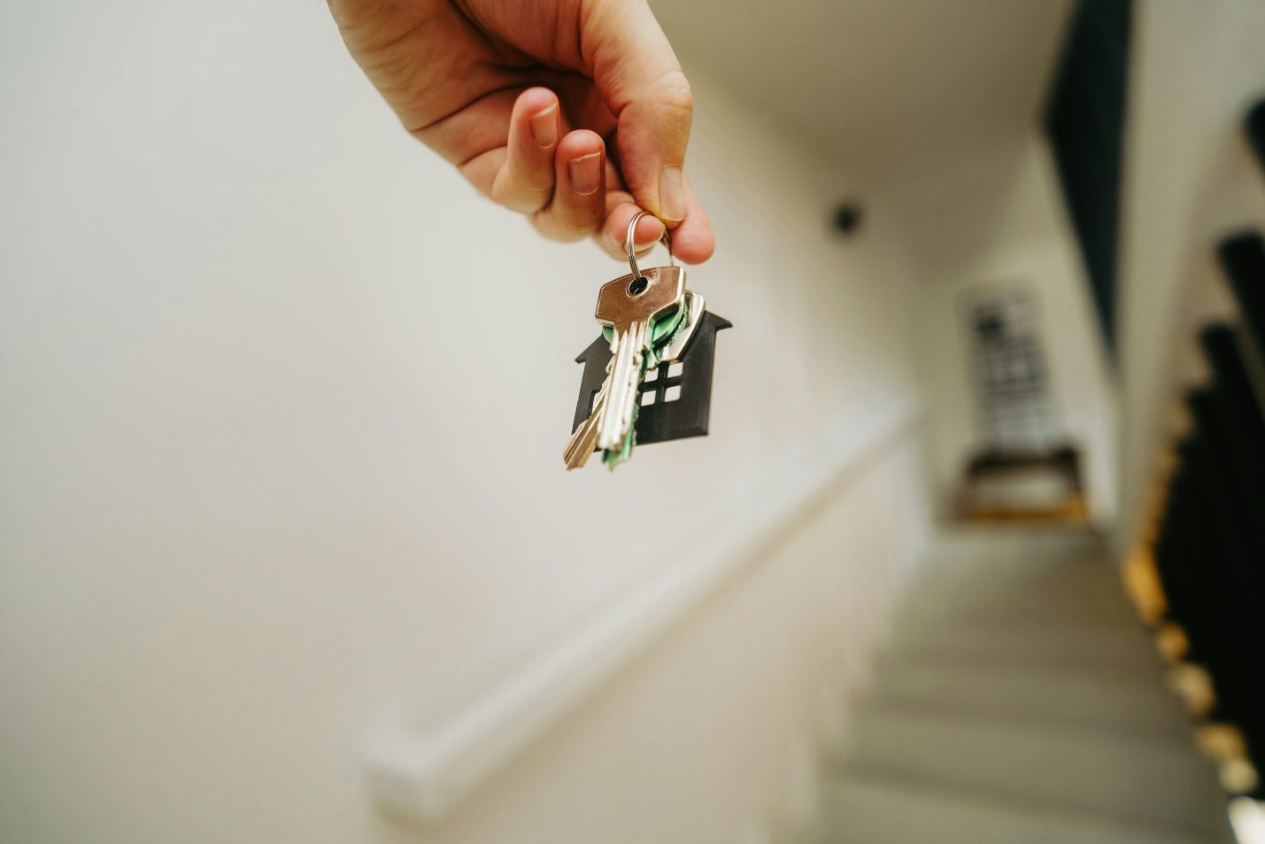 A person holding a house shaped keychain with several keys