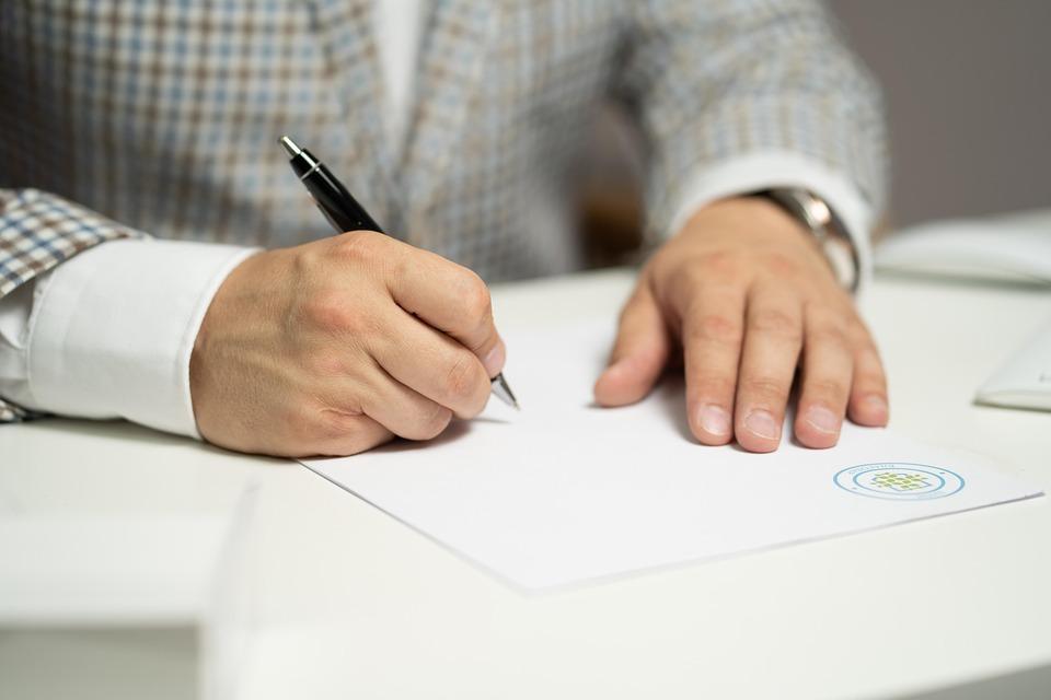 close-up of a man signing a document 
