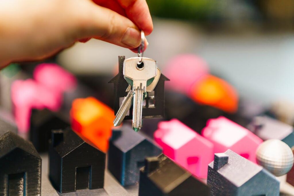 A person holding a house key above miniature houses