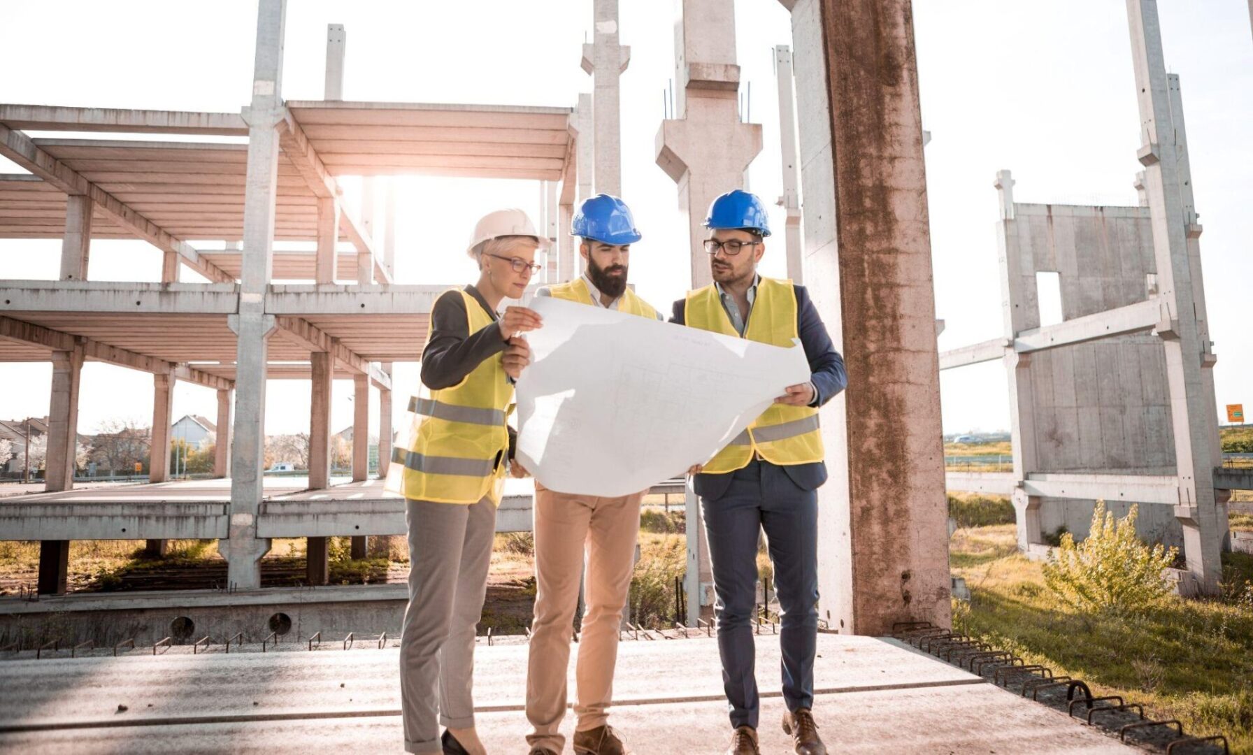 three workers holding up a sheet of construction plans