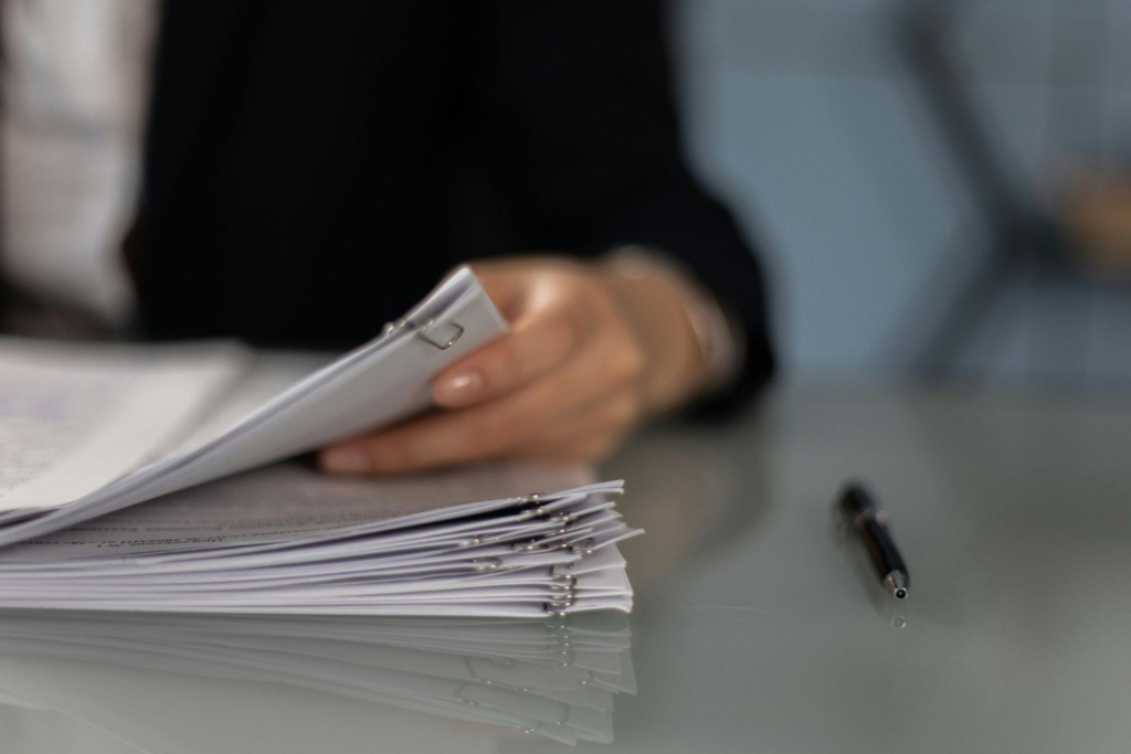 Person reviewing a stack of documents at a desk
