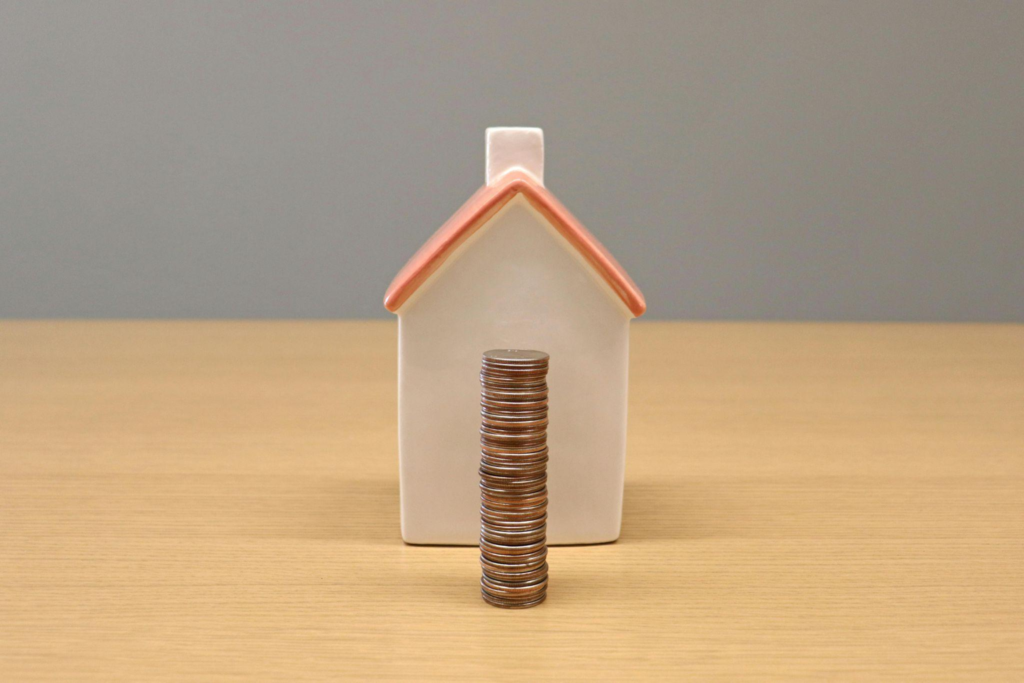 House model placed behind a stack of coins