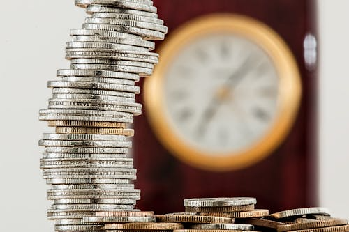 A tower of coins with a clock in the background.
