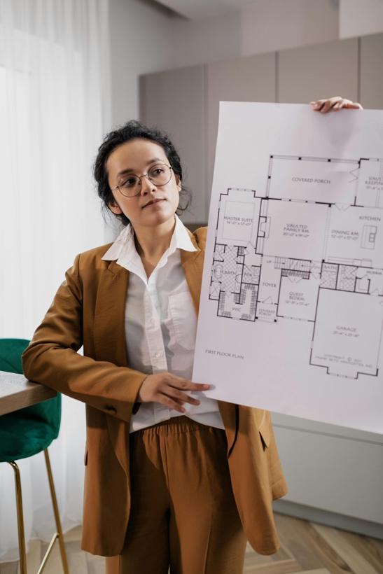 Woman in business attire holding a residential floor plan document