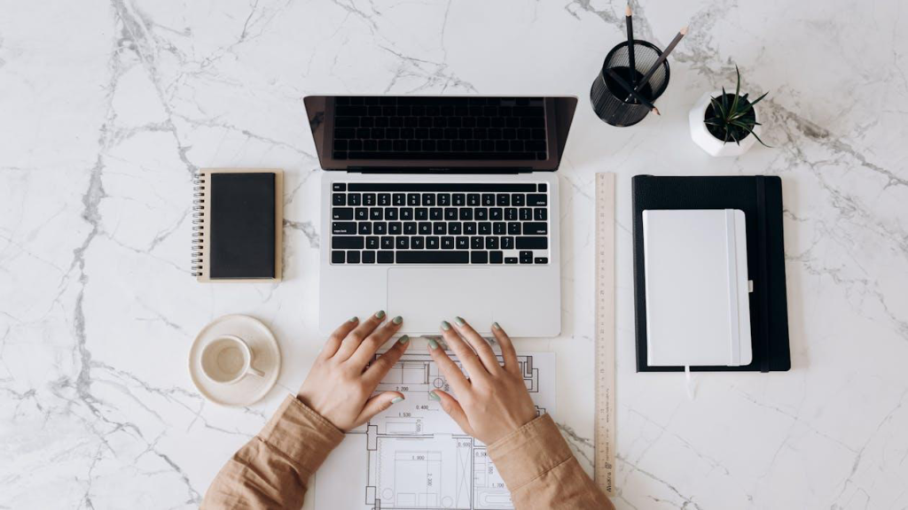 Laptop and architectural plans used for budgeting a large-scale construction project