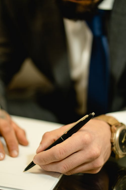 An image of a person pointing at something with a pen on paper 