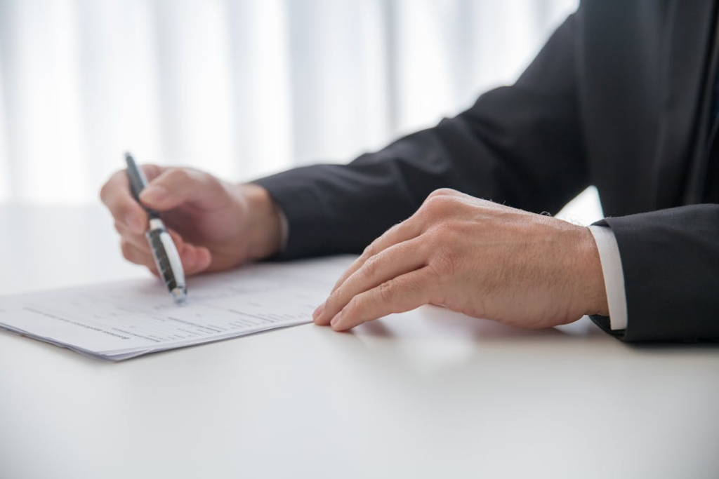 An image of a person pointing at something with a pen on paper 