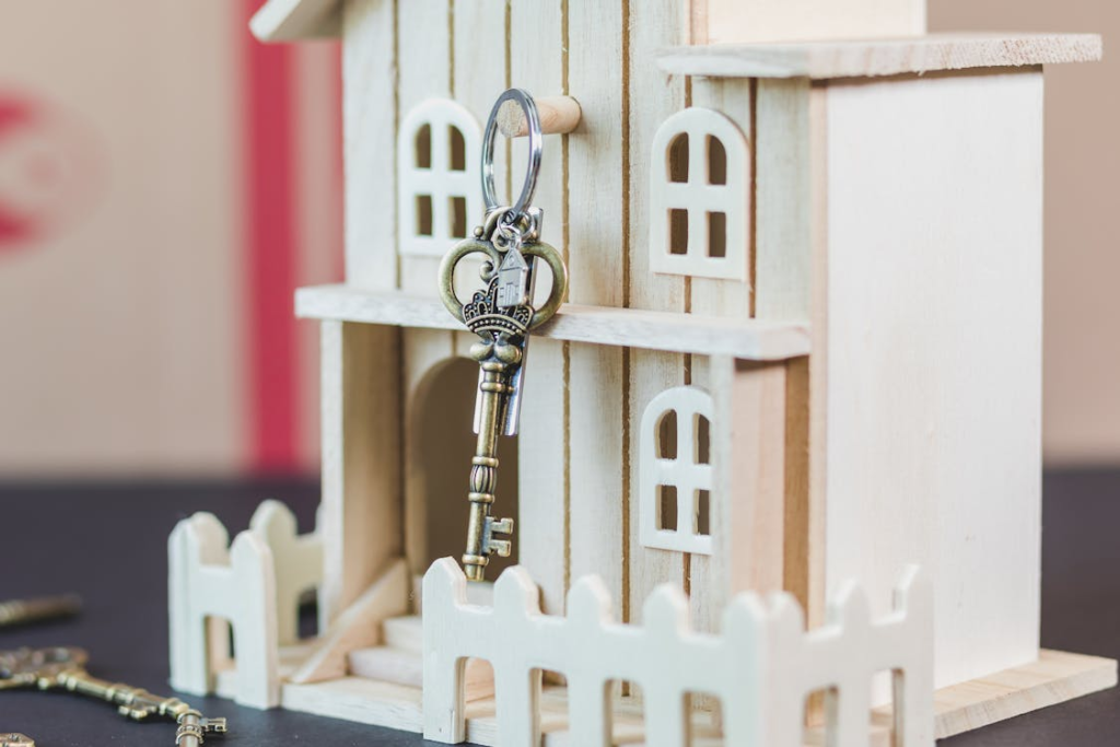 Key hanging from a small wooden dollhouse representing property investment