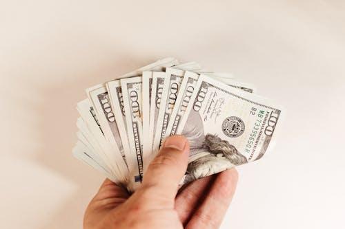 A hand holding US dollar bills