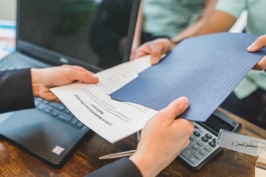 a lender handing over loan application forms to a client