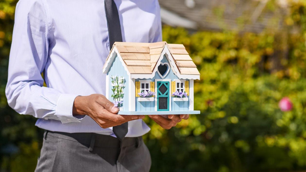 close-up of a real estate agent holding a miniature wooden house