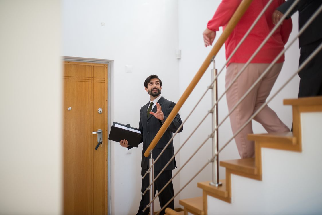 a man standing at the bottom of the stairs talking to clients