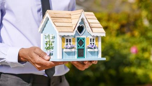 A man holding a wooden house miniature