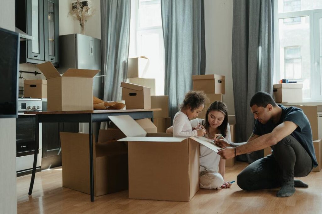 Smiling family carrying cardboard boxes into home