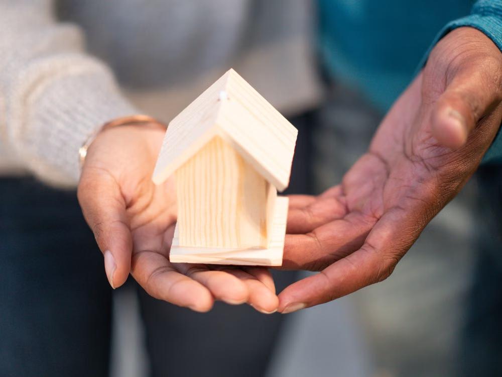 A couple holding a miniature of a wooden house