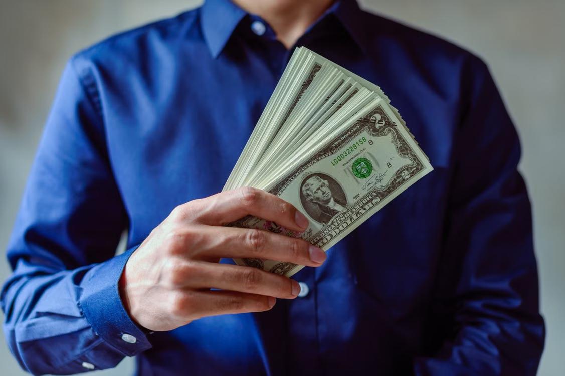 A person holding US dollar bills