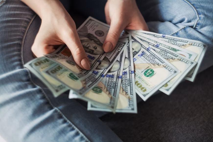 A person holding US dollar notes